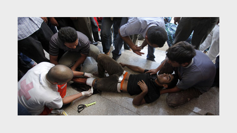 Четирима мъже се грижат за ранен мъж, който лежи на земята © Associated Press / Източник: AP