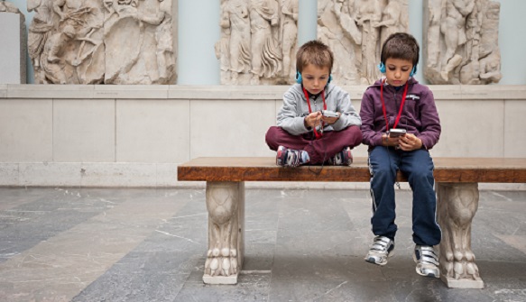Two boys sitting on a bench in a museum