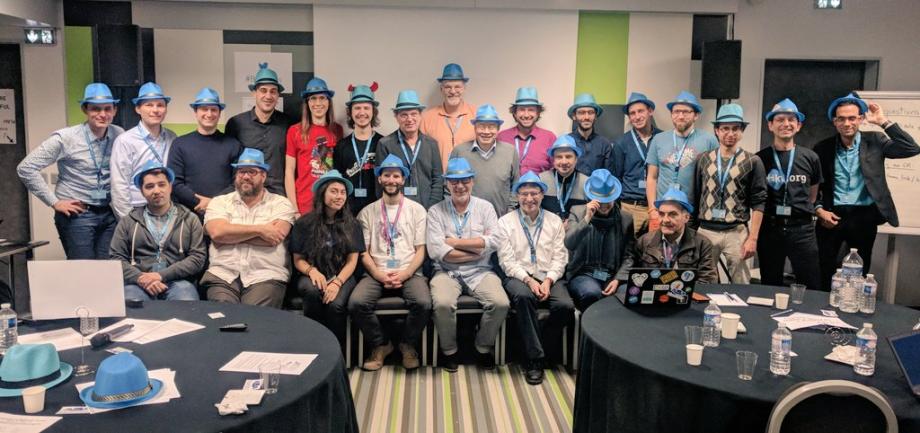 The image shows a group of people wearing blue hats