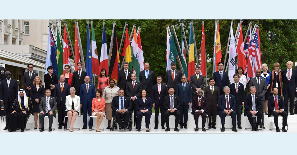 Social ministers from several countries, including the EU, pose for a photo in front of flags for each respective country