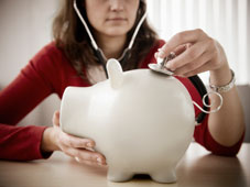 Woman using a stethoscope on a piggy bank
