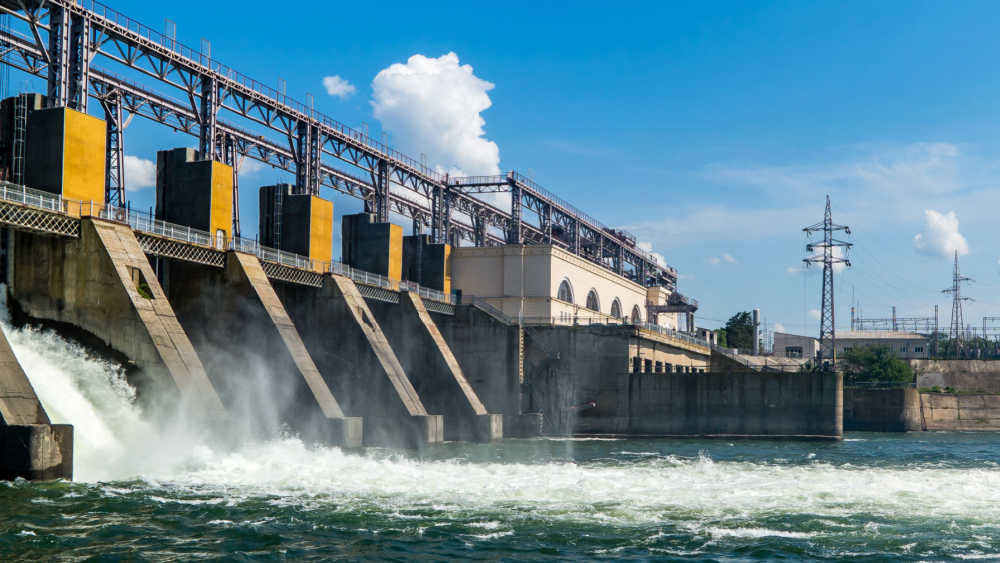 The picture shows a big dam with water coming out of it