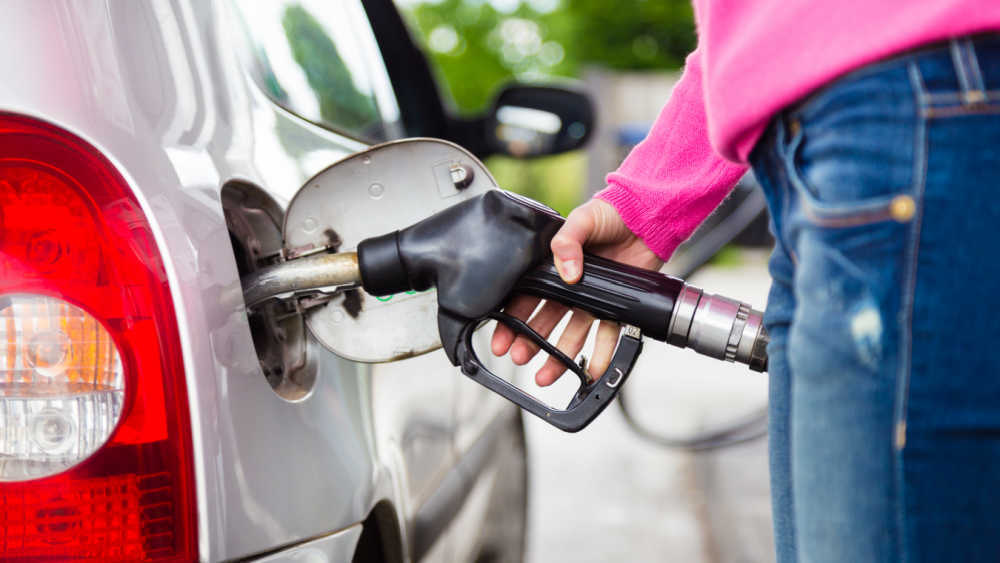 Closeup of woman pumping gasoline fuel in car at gas station.