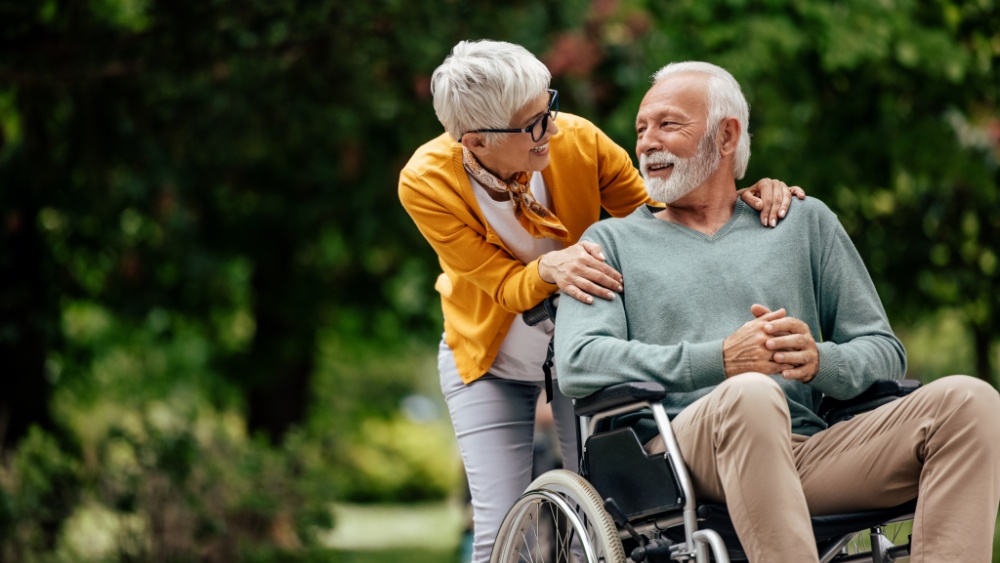 Senior man in wheelchair, being taken care by his wife