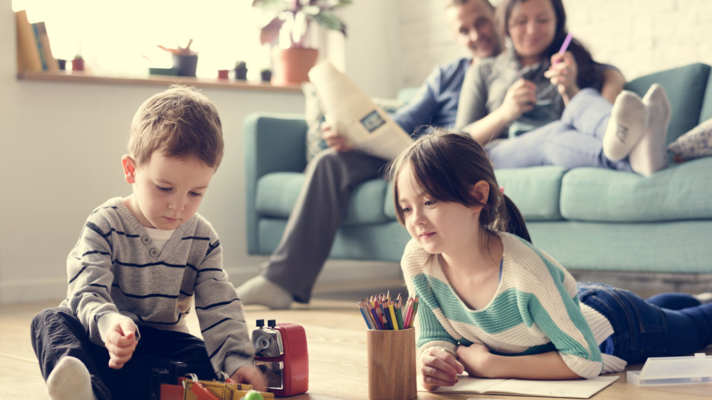 2 children on the floor and 2 adults sitting on a couch.