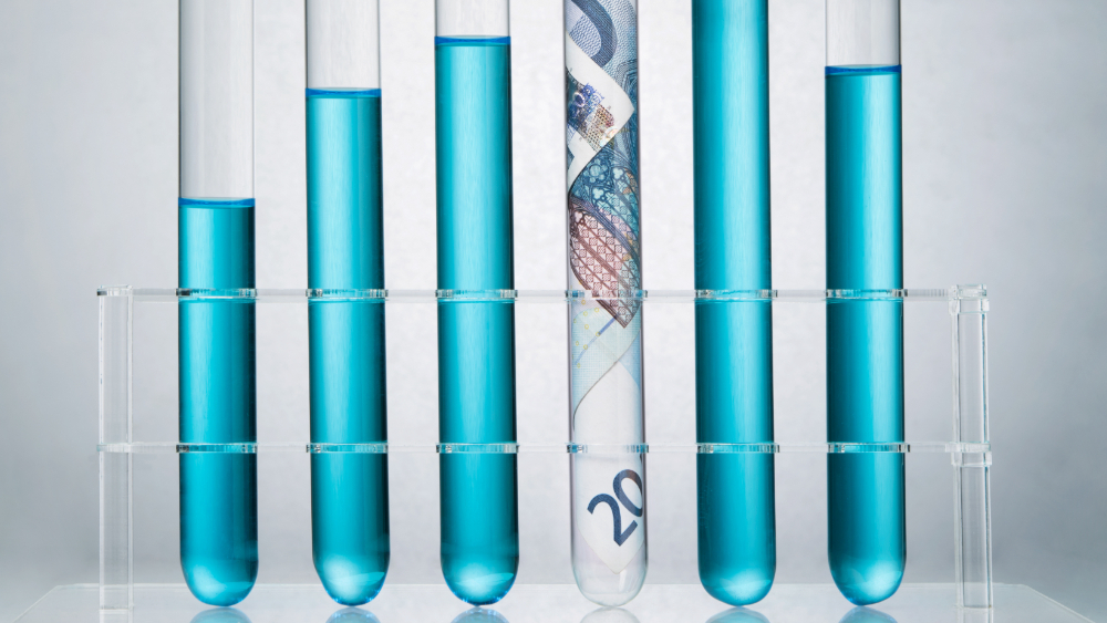 Image: Rolled up Euro paper banknote in a test tube rack representing the costs of R&D research