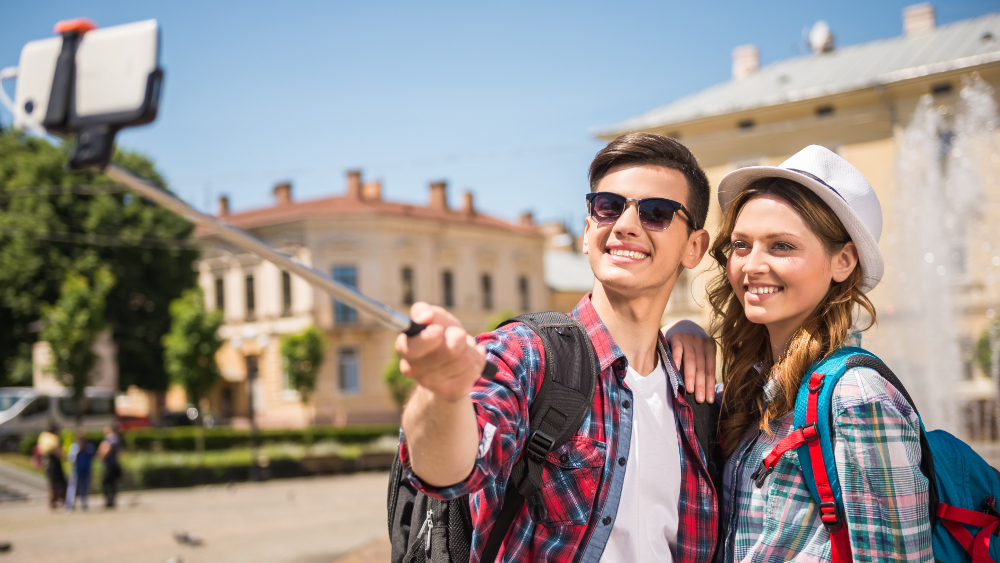A young man and woman taking a photo using a selfie stick