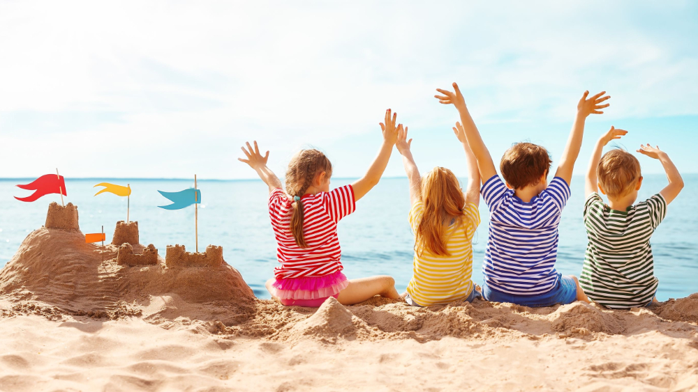 Image: Four happy children sitting on the sea coast and raising up their hands