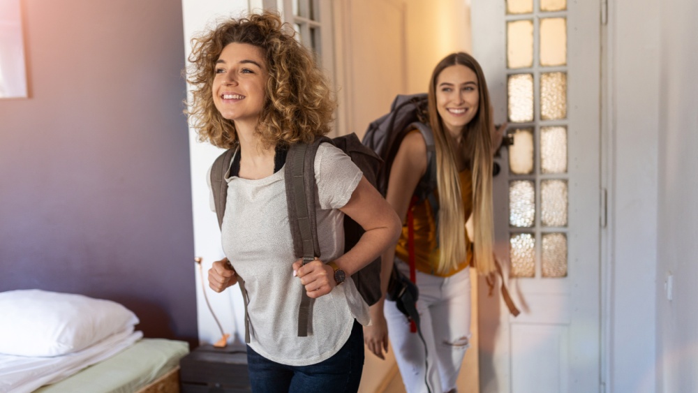 Two young women with backpacks entering their accommodation.