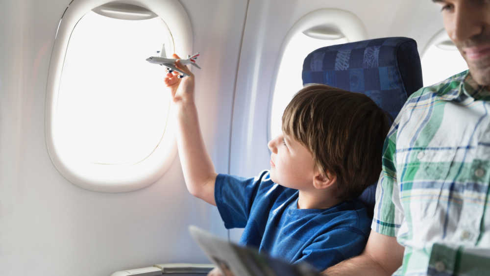 A boy traveling on an airplane and playing with a toy airplane