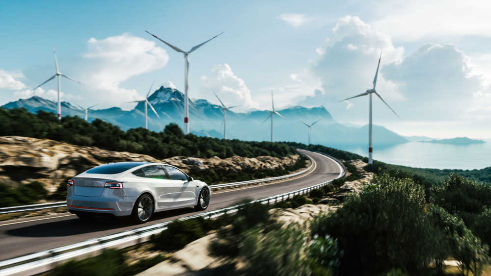 a car driving along a road with wind turbines nearby