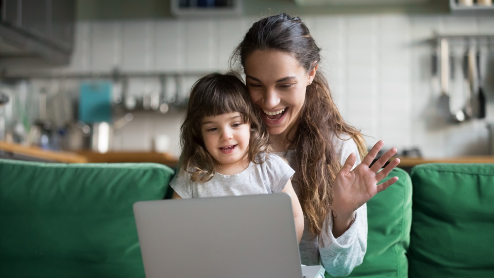 A women and a child smiling an waving while looking at the laptop.