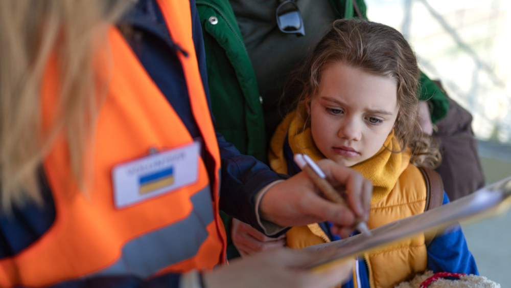 A child waiting while a person wearing florescent vest is filling out the form.