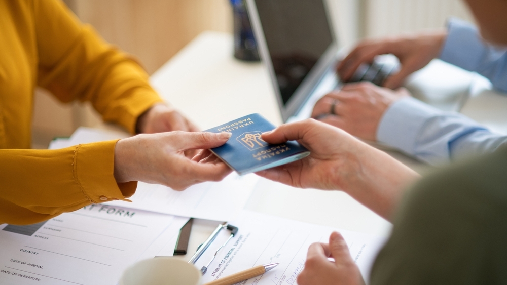 Person handing a passport over the table.