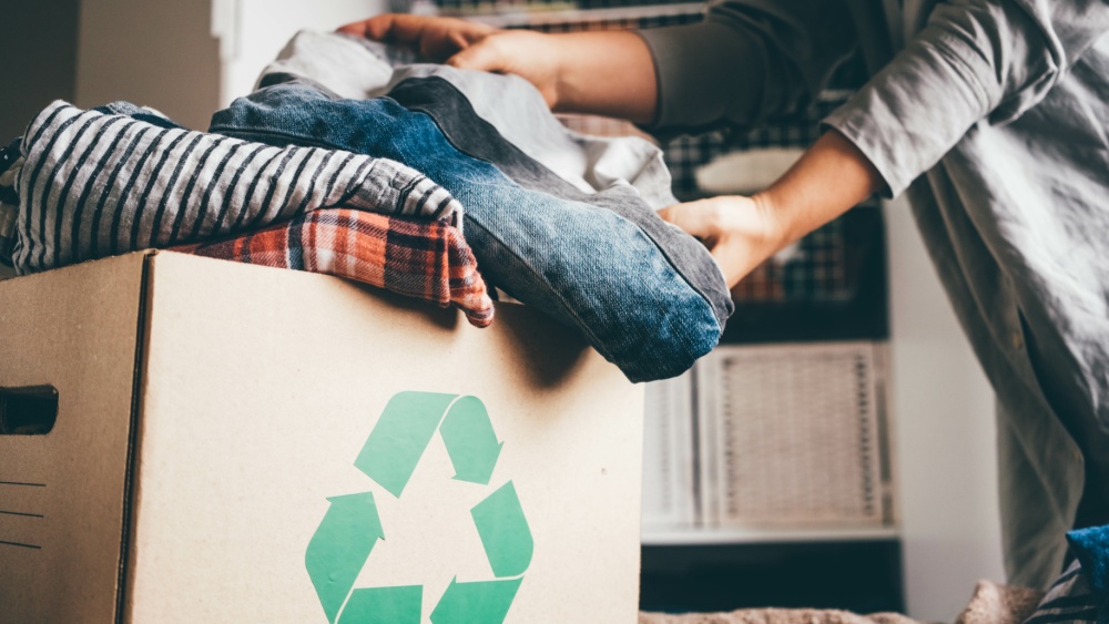A person storing clothes in a recycling box.