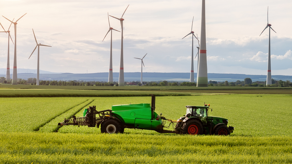 Tractor in a field in front of wind turbines.