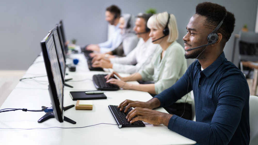 Five people look into their desktop screens wearing headphones.