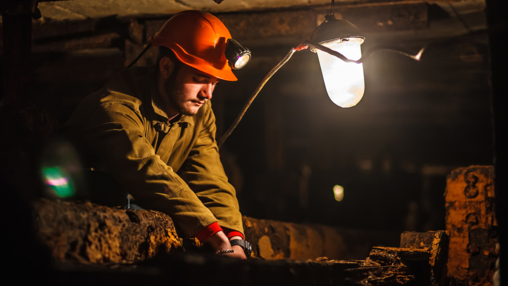 A worker with a helmet is working underground in a cave