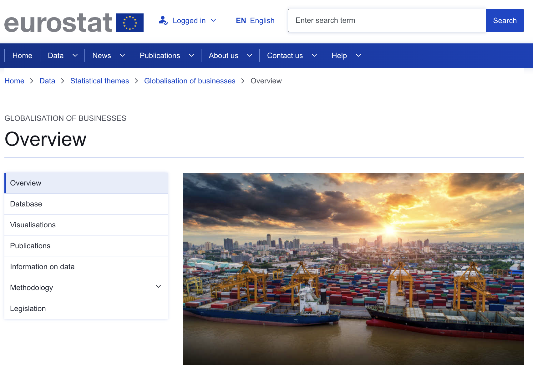 Στιγμιότυπο οθόνης της ιστοσελίδας της Eurostat για την οικονομική παγκοσμιοποίηση που σχετίζεται με τις επιχειρήσεις.  Η εικόνα δείχνει ένα εμπορικό λιμάνι το ηλιοβασίλεμα με εκατοντάδες κοντέινερ διαφορετικών χρωμάτων αποθηκευμένα σε οικόπεδο κοντά στο νερό, δίπλα σε φορτηγά πλοία.