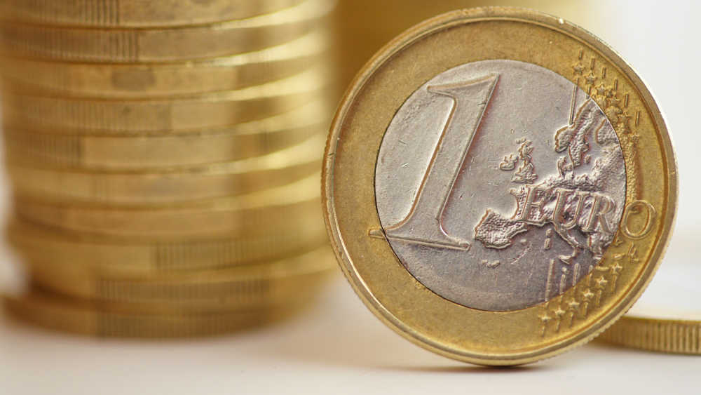 Euro coin next to a stack of coins.