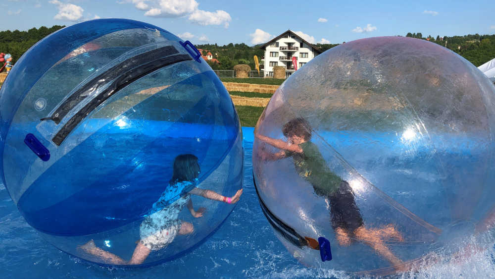 Two children play in bubble balls on water