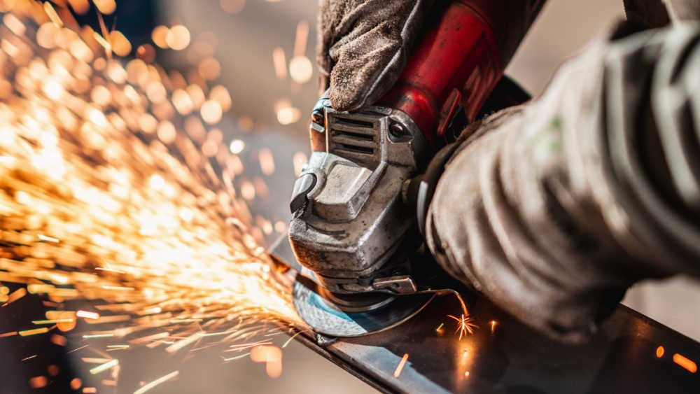 person operating heavy machinery with sparks coming out if it.