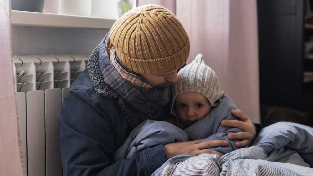Man and son wearing warm clothing feeling cold at home