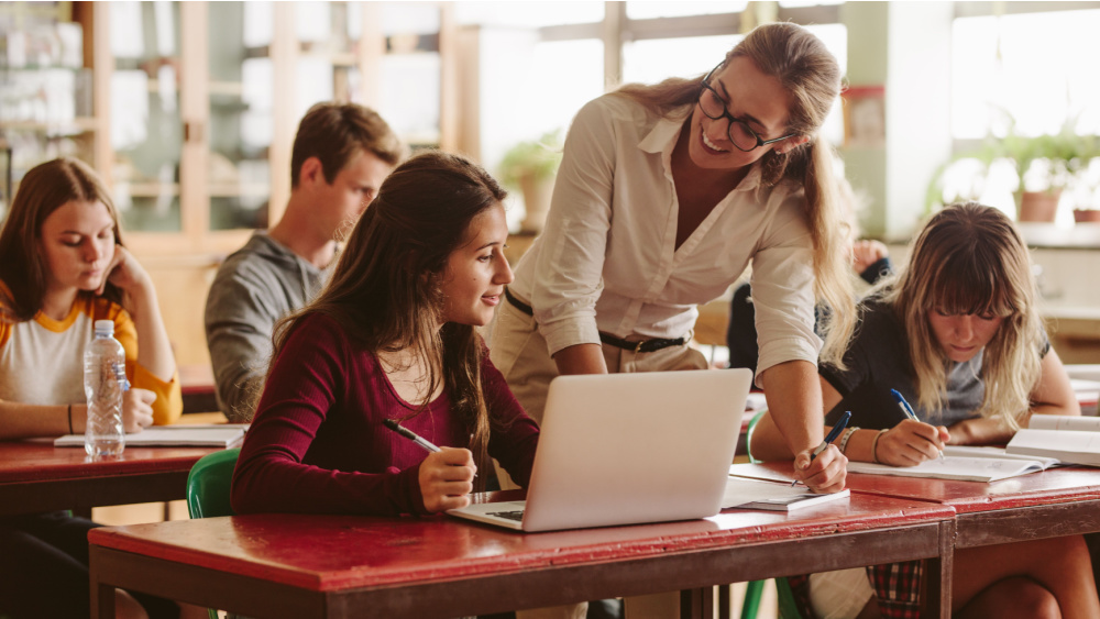 teacher talking with students in the classroom.