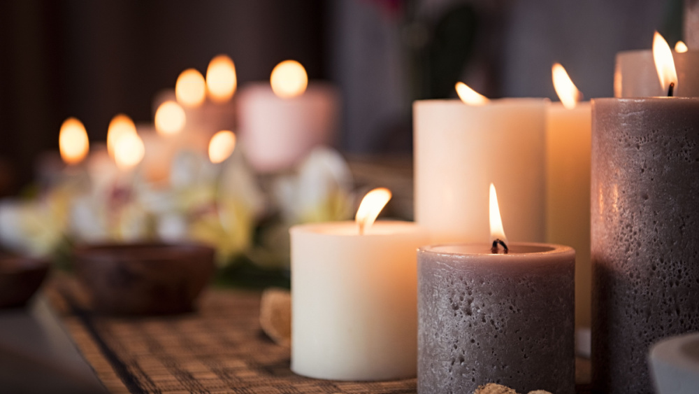 A lot of lit candles in different sizes are standing on a mat as decoration