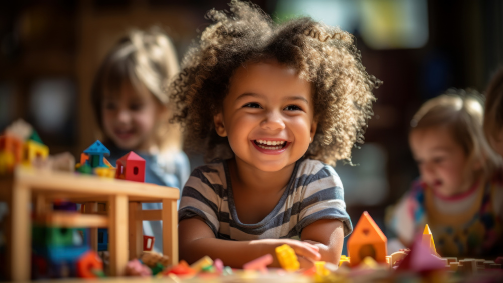 Three children playing with toys with one of them in focus, laughing.
