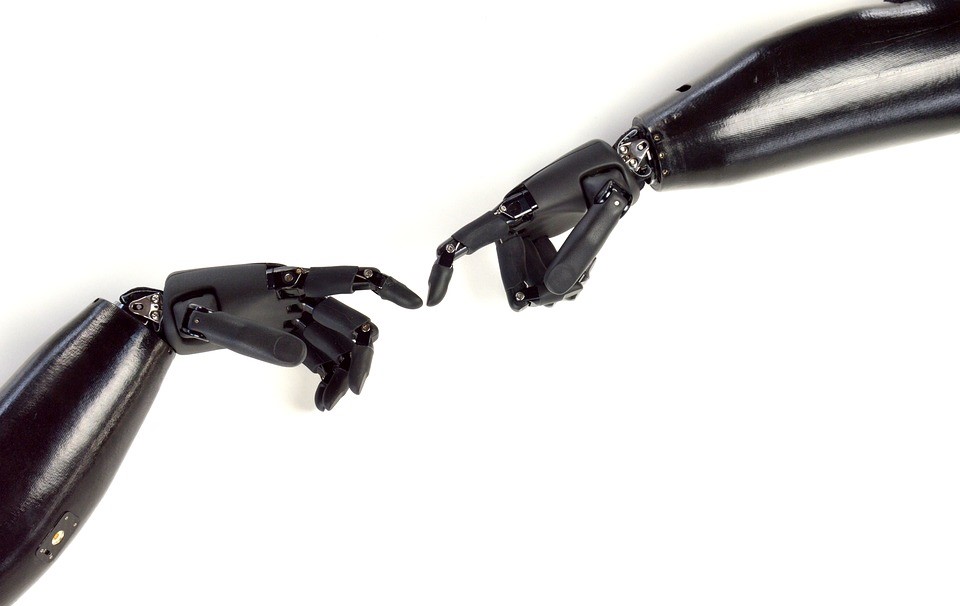 Two robotic arms touching index fingers of each other