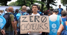 A man holding a sign that reads 'Zero Unemployment' in french