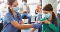 Sairaanhoitaja antaa rokotuksen tytölle