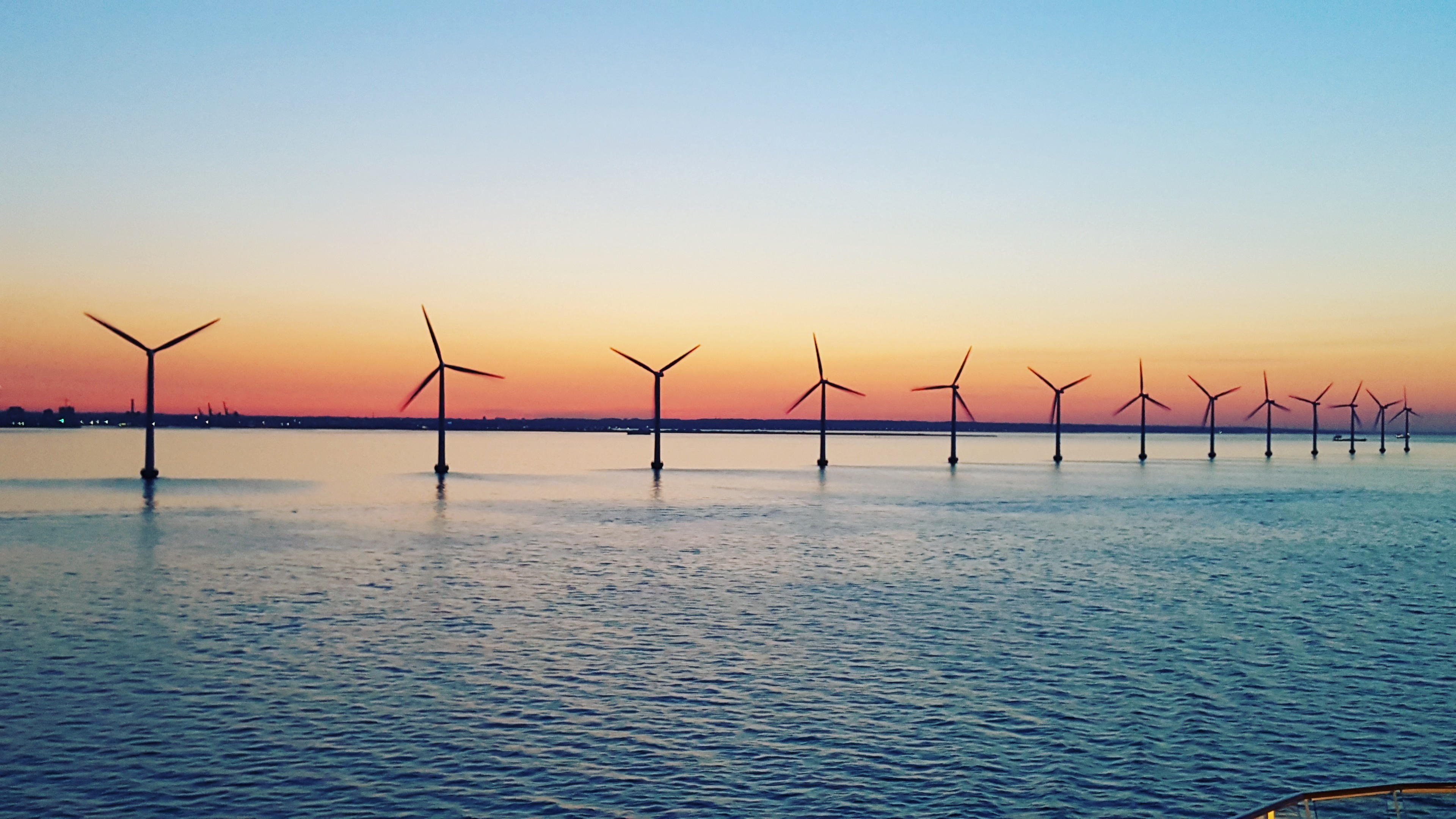 A dozen coastal wind turbines at dusk