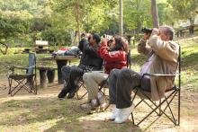 Group of seated people with binoculars birdwatching. 