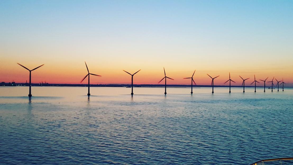 A dozen coastal wind turbines at dusk