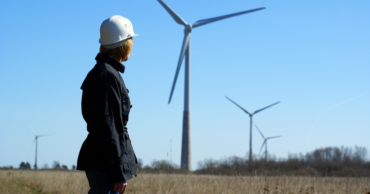 Woman engineer or architect with white safety hat and wind turbines on background