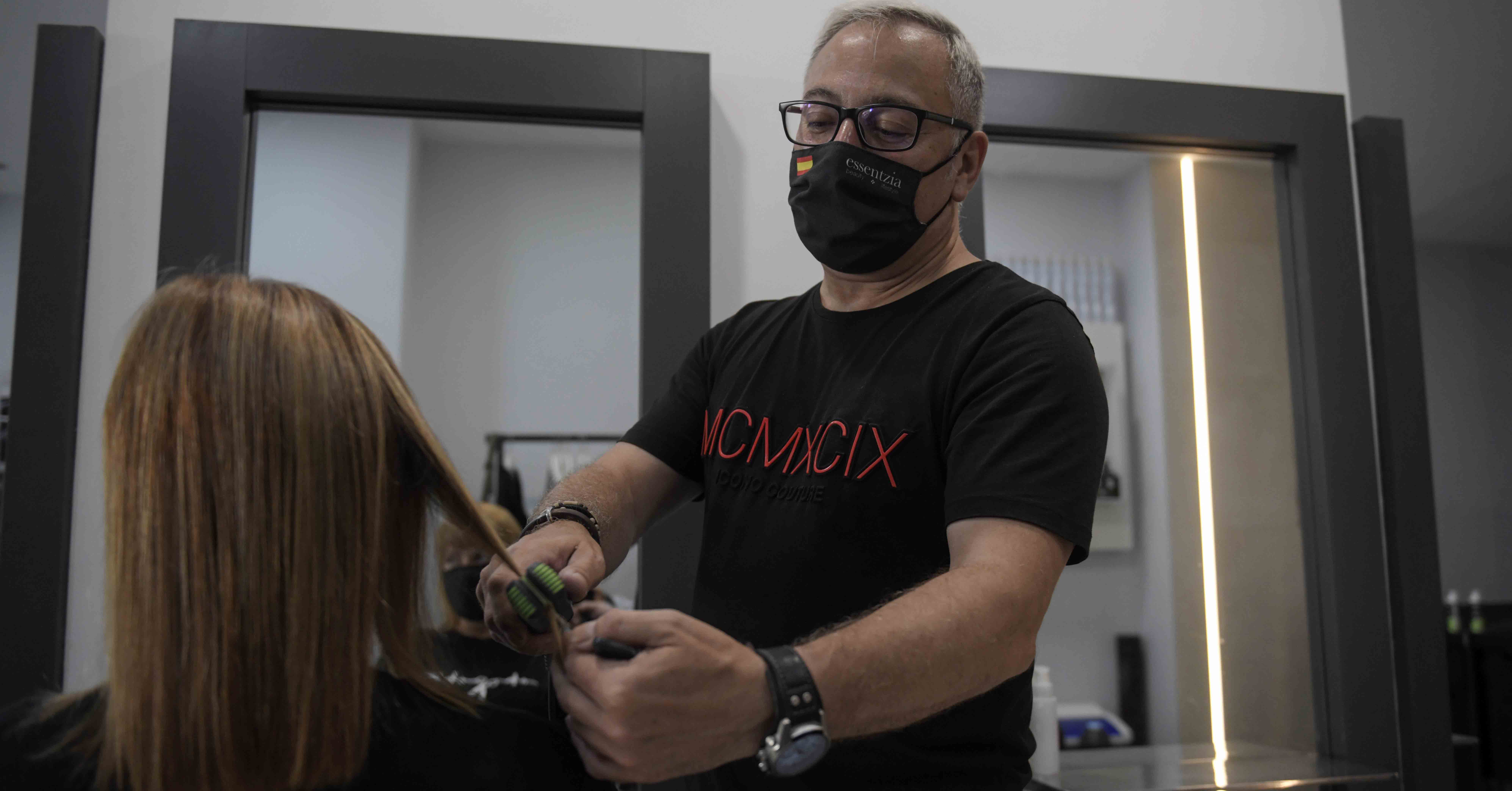 An hairdresser cutting his client's hair in his hair salon in Madrid, Spain