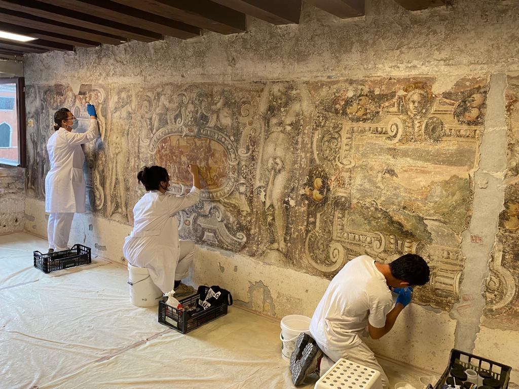 People restoring and old mural baroque painting