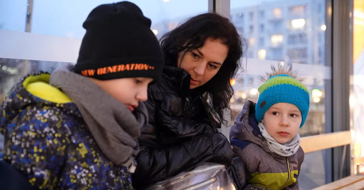 A Ukranian mother and her two sons sitting in a bus stop