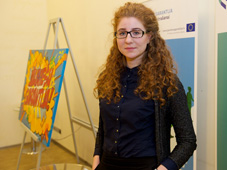 Gerda in front of Latvian Youth Guarantee poster next to colourful canvas with the words 'Youth Guarantee' in Latvian