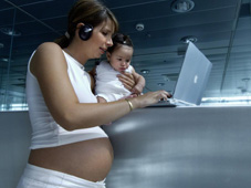 Femme enceinte tenant un bébé, travaillant sur un ordinateur