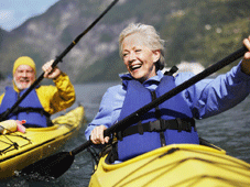Older man and woman paddling in canoes