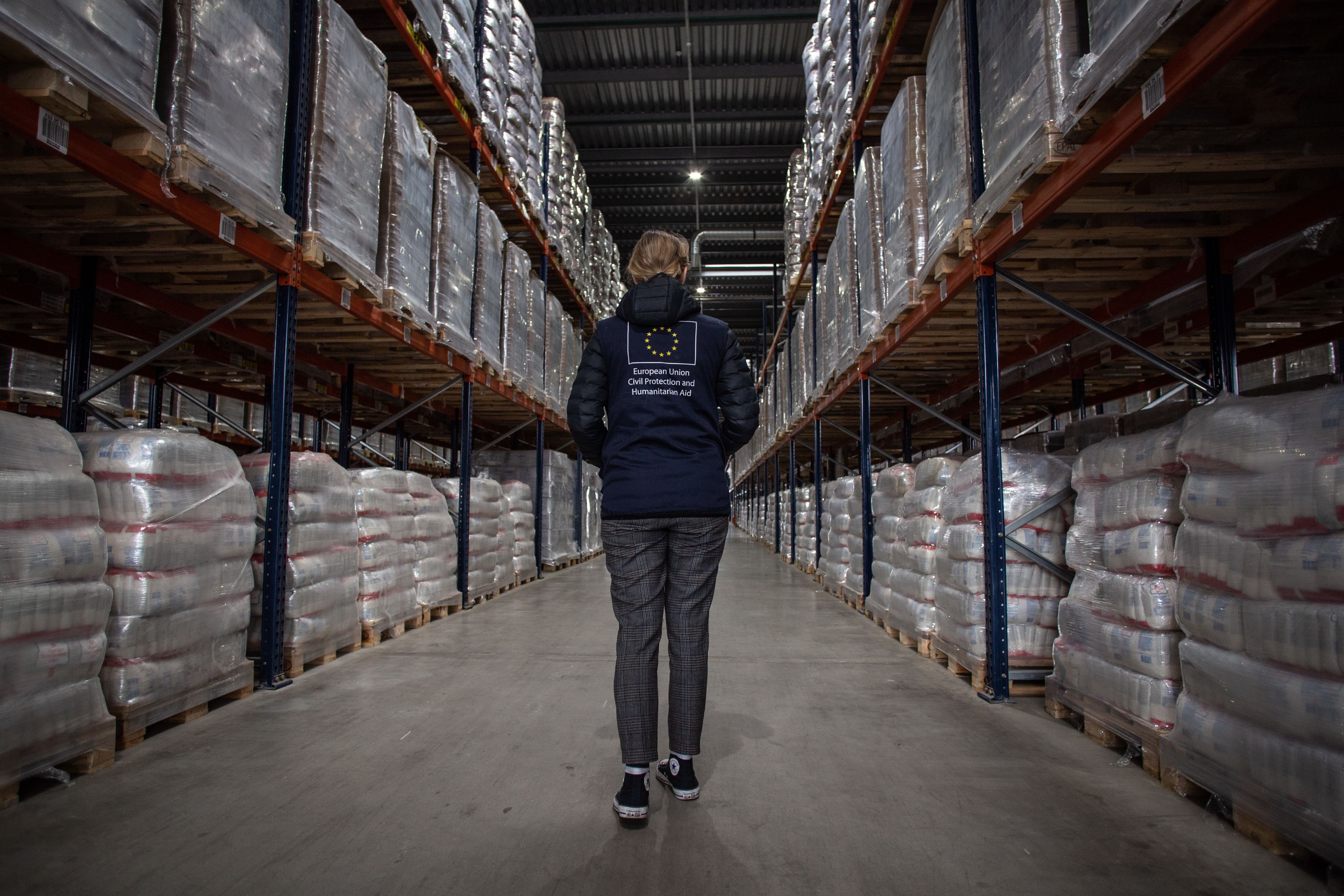 A person walks through a warehouse filled with stockpiled equipment.