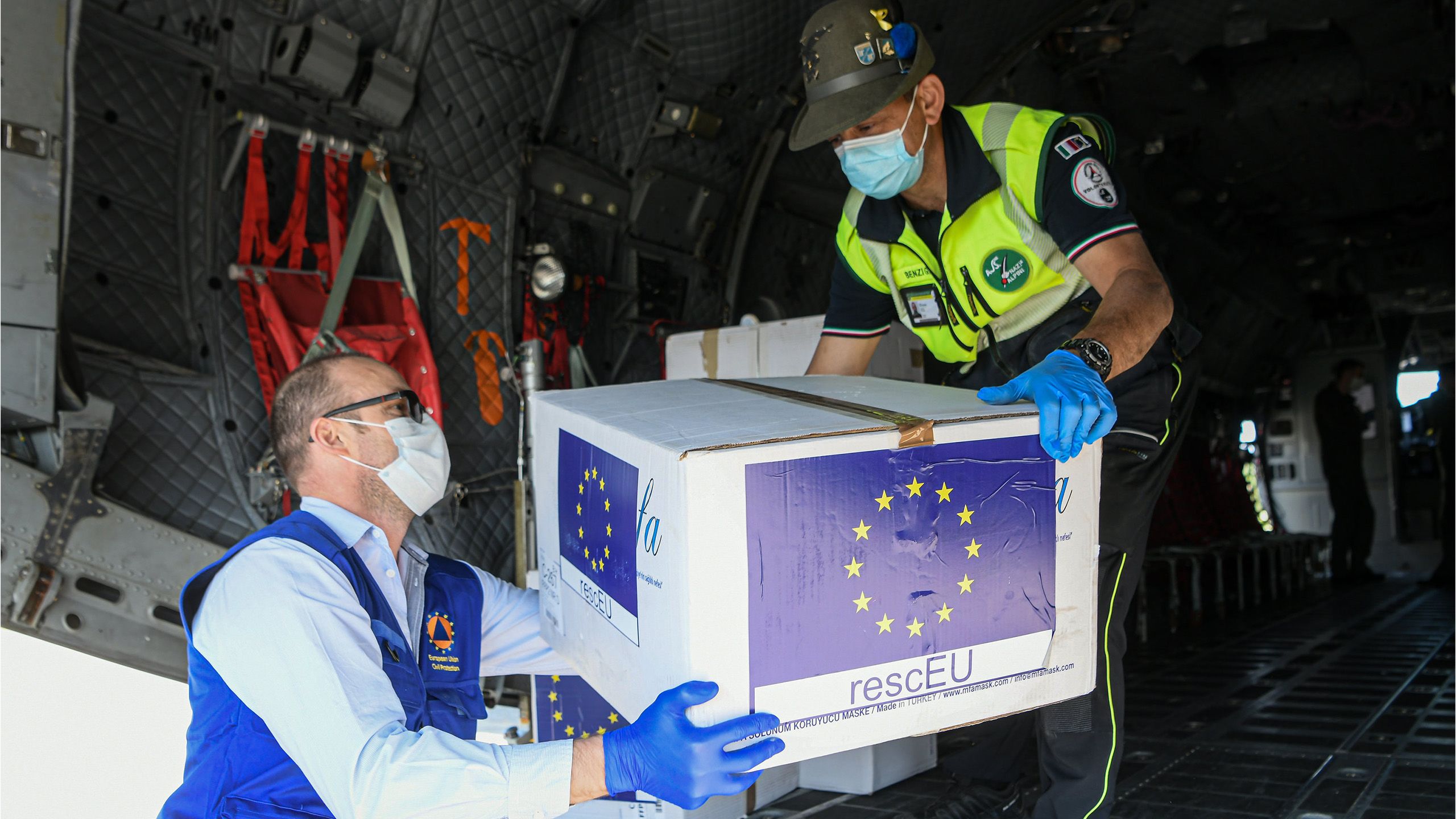 Two people unload medical supplies from a plane.
