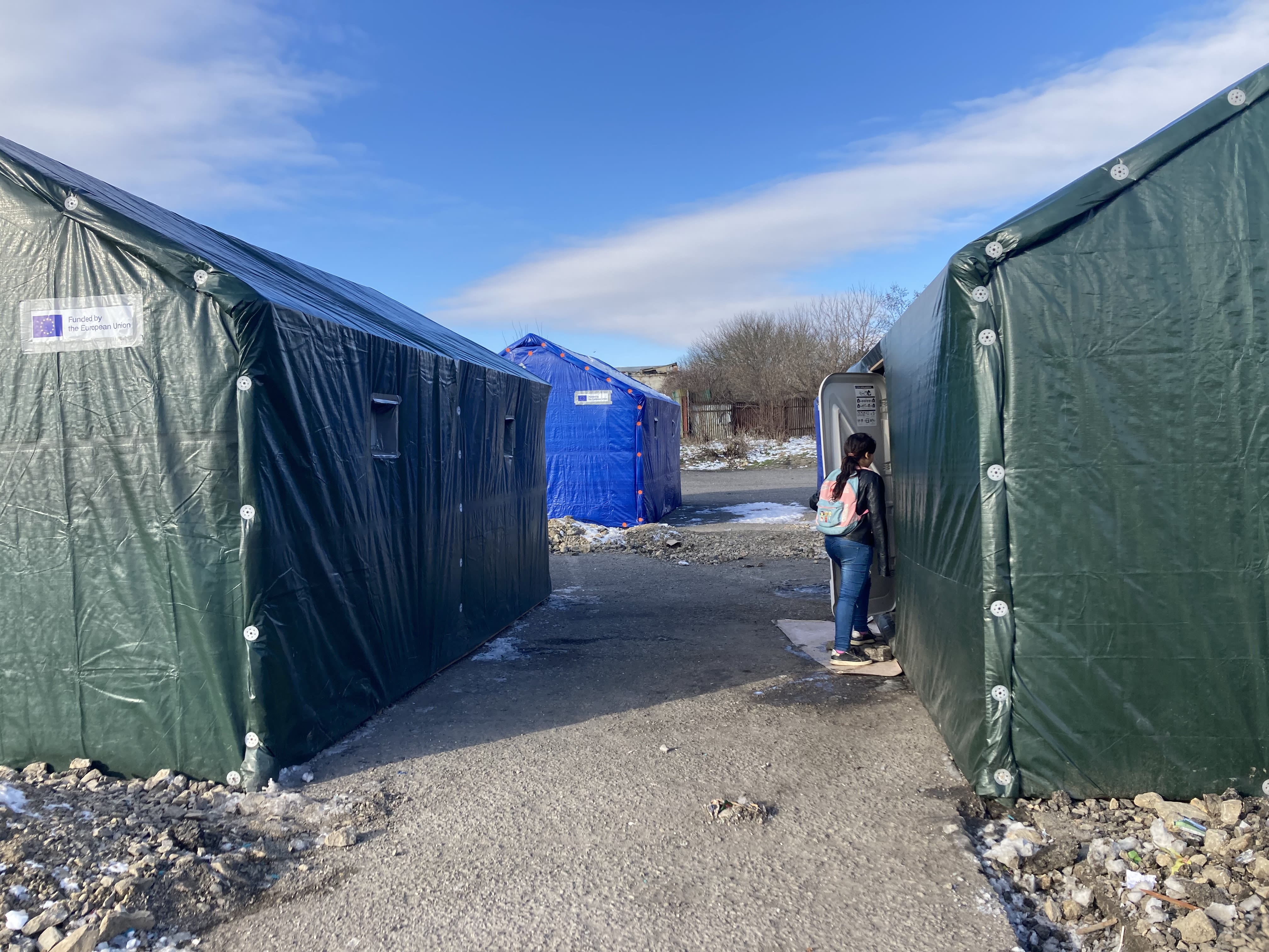 A person stands in front of an emergency shelter.